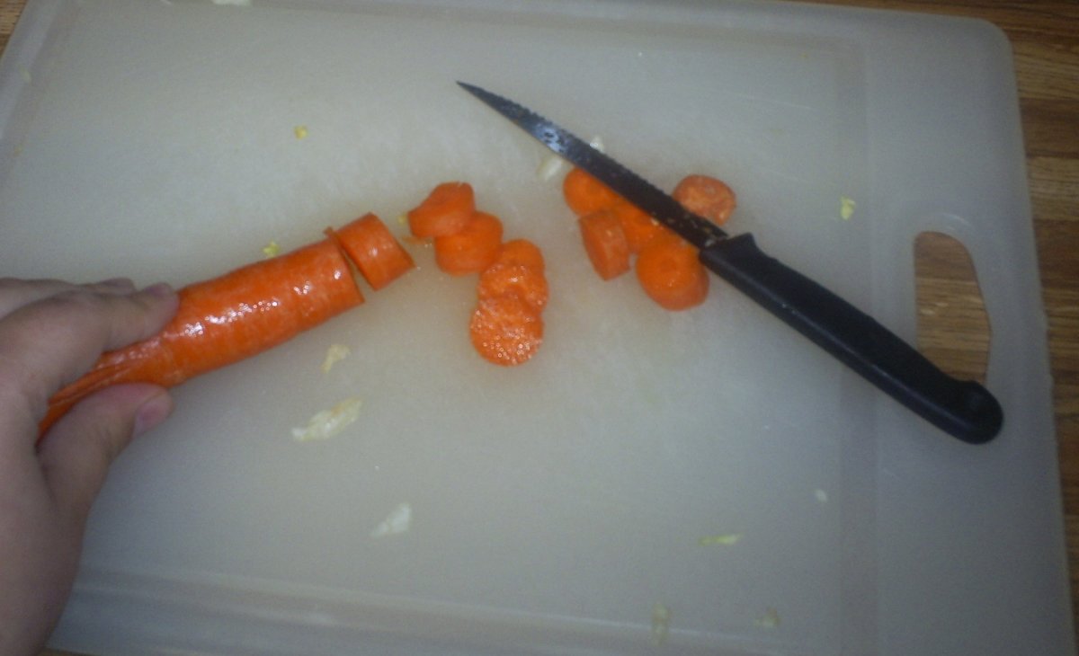 Chop a carrot on a cutting board.