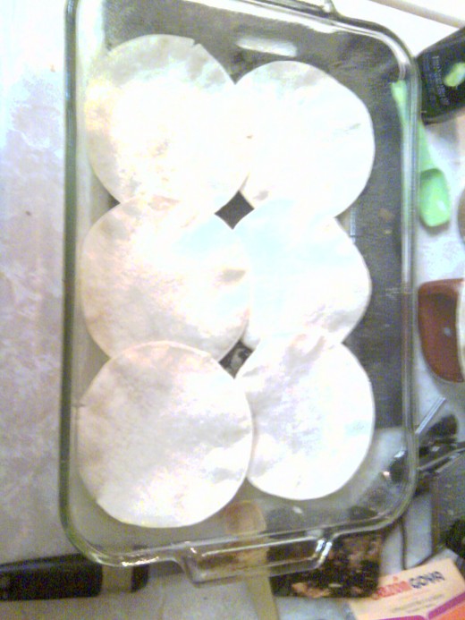 The bottom layer of tortillas are placed in a butter sprayed dish like this.