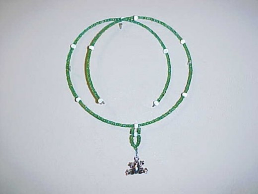 The Charmed Frog-This piece is made with memory wire, green seed beads with a blue hint (glass), glass silver beads, and a pewter frog charm. 
