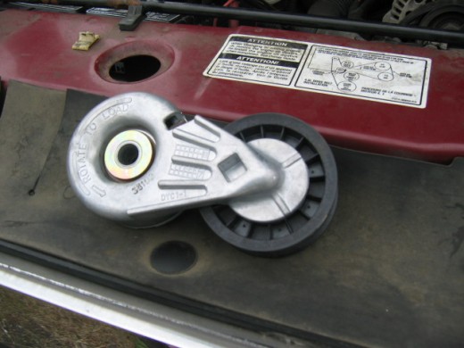Belt tensioner with hole for ratchet, and decal showing belt routing