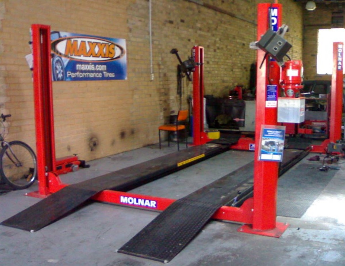 This four post vehicle hoist is a four ton with a sliding jacking beam and wheel alignment pads.