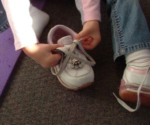 A girl learning to tie her shoe. Image by Tory Byrne, Stock.xchng