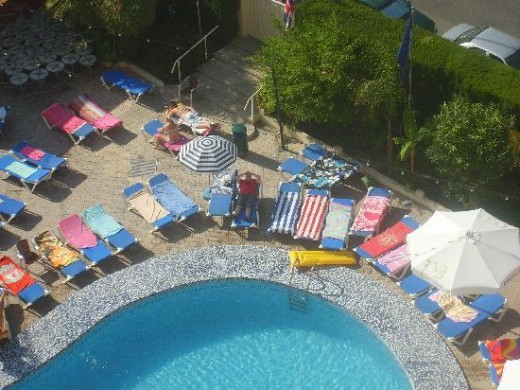 view of towel-covered but empty sunbeds round the pool
