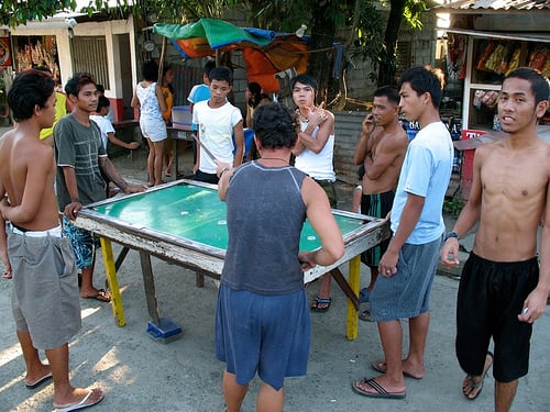 Typical Filipino makeshift billiards table being used outdoors. Filipino males wear shorts and go sleeveless or shirtless because of the hot and humid weather.