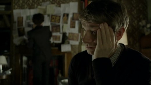 John and Sherlock (background) at 221B Baker Street.