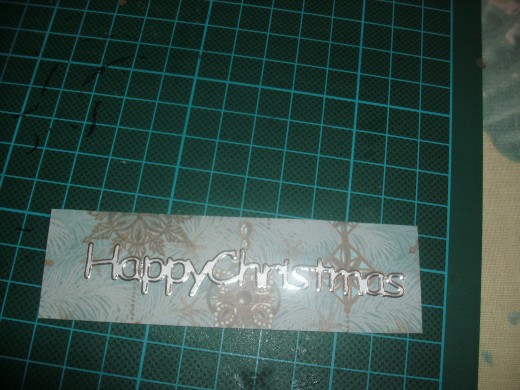 Happy Christmas sticker on card covered with contrasting paper