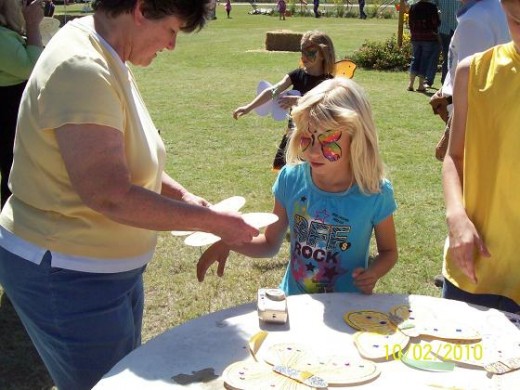 An expectant  little girl gets her butterfly decoration to wear in the Butterfly parade.