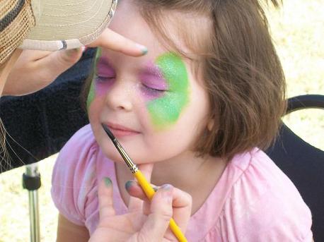 She is sitting motionless -- frozen with anticipation -- as the face-painter transforms her into a fantasy butterfly.