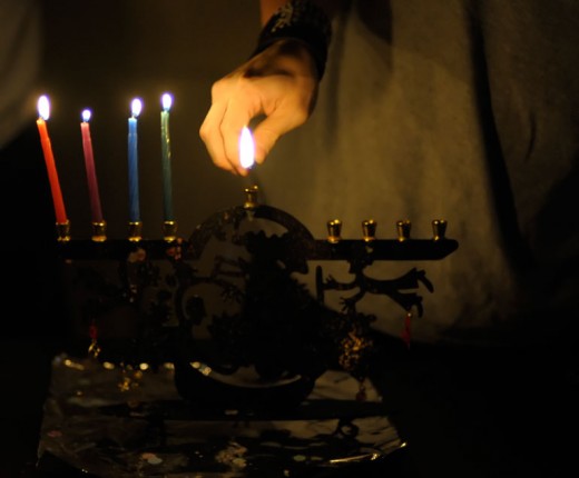 Using the shamash to light the menorah (or chanukiah) on Hanukkah