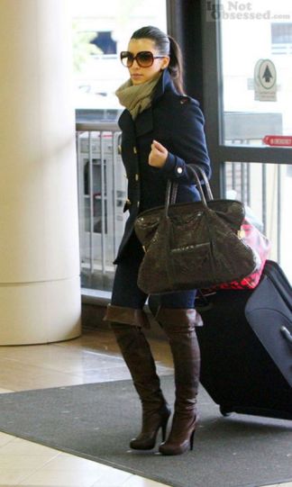 Here she is traveling with luggage yet rocking thigh boots.