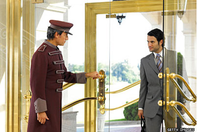 Uniformed Hotel Bus Boy Opening Door for Gentleman in a Grey Suit
