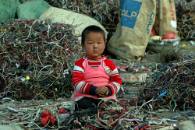 A Chinese child sits amongst a pile of wires and e-waste. Children can often be found dismantling e-waste containing many hazardous chemicals known to be potentially very damaging to children's health.