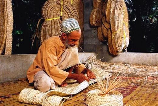 Old man weaving a mat from the date palm leaves