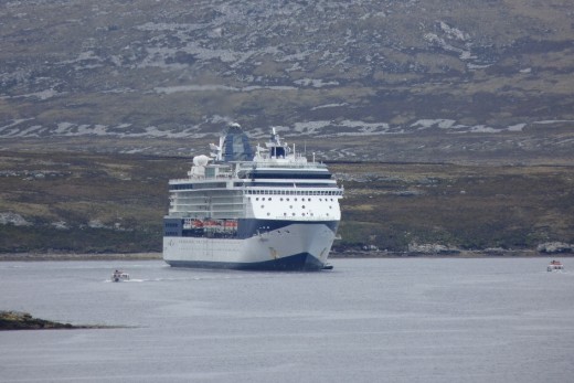 The Celebrity Infinity in Stanley Harbour with a tender carrying passengers between the ship and Stanley.
