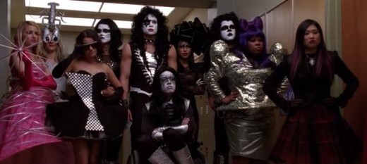 The glee kids standing up to the football players in their costumes.