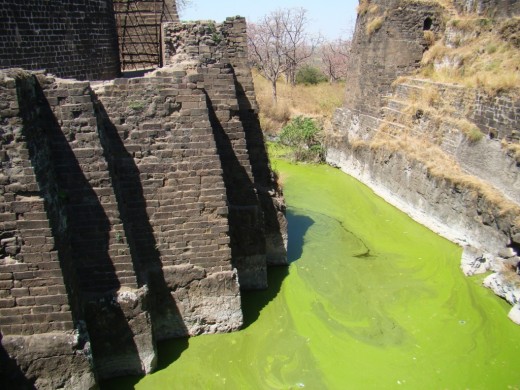 The deep moat surrounding the main fort; the green color of the water is due to algae