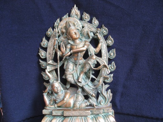 Shiva is dancing in his ring of fire. He dances on the body of the demon who seems to be smiling.