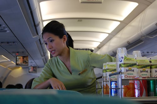 A flight attendant conversing with passengers while serving beverages.