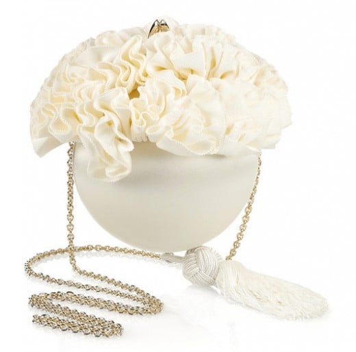 Christian Louboutin's spherical ivory satin clutch with a ruffled floral grosgrain trim is a fresh and fabulous bridal style. Carry this tasseled piece with an asymmetric off-white dress and gold lace-up stilettos for a cool, contemoporary look. 