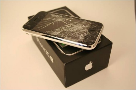 A severely shattered iPhone that was dropped face down onto asphalt.