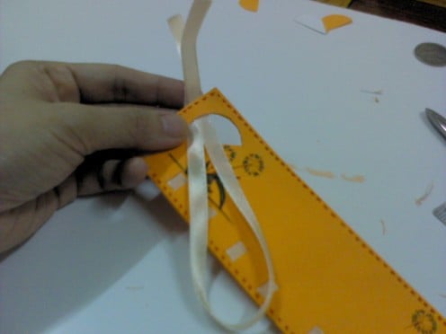 Fold ribbon into 1/2. Pull the ribbon into the semi-circle hole half-way.