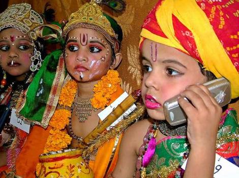 Indian kids as Lord Krishna and Balram talking on the cellphone.