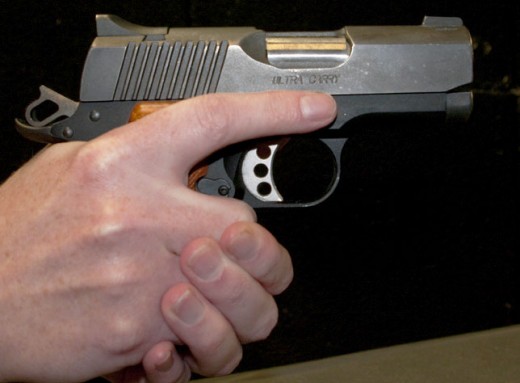 The trigger finger is completely out of the trigger guard and resting alongside the frame of the pistol.
