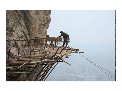 The workers are building a plank road on the side of the mountain that, once it is  finished, will stretch for 3km (9843 ft) and be China 's longest sightseeing footpath