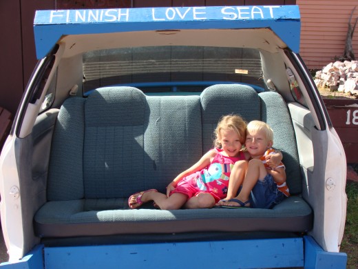 Grace and Alex sitting in the backseat of a car in DaYooper's Tourist Trap.  They call this a 'Finnish Love Seat.'