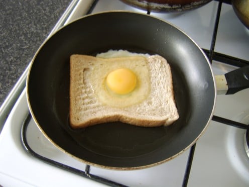 The egg is carefully poured on to the bread so that the yolk slips in to the hole