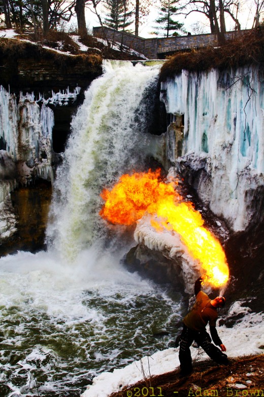 Heartburn Shawn Sabot breathing fire in front of a still-frozen Minnehaha Falls in Minneapolis, MN.