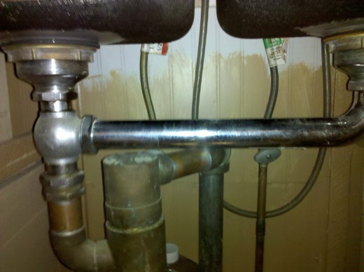 Trap and Drain System underneath a Double Kitchen Sink. Notice the Bottle Trap in the center.