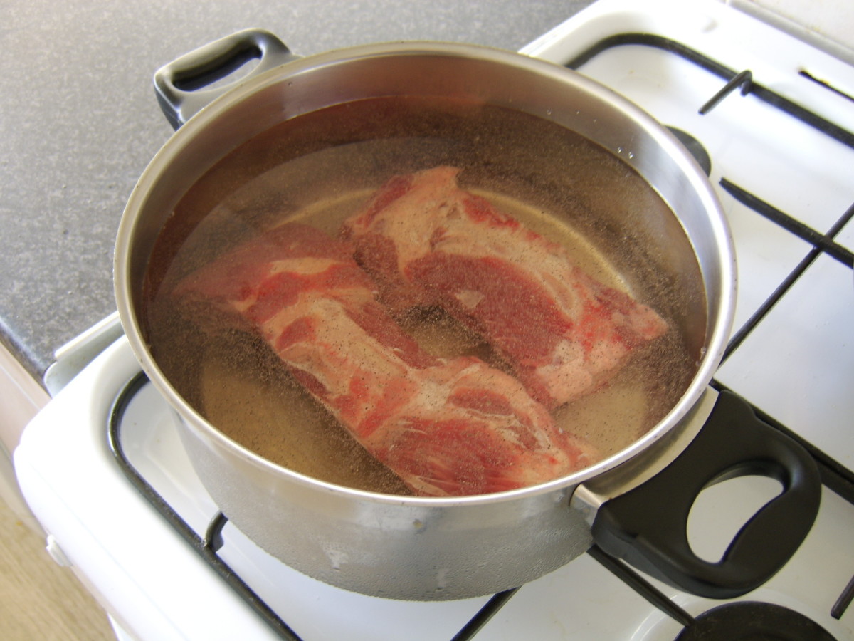 The beef bones are seasoned and enough cold water is added to come within an inch of the rim of the pot