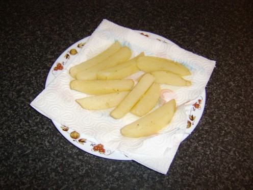 The once fried, still soft and pale chips are drained on kitchen paper