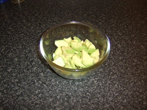 The peeled avocado halves are chopped and added to a mixing bowl