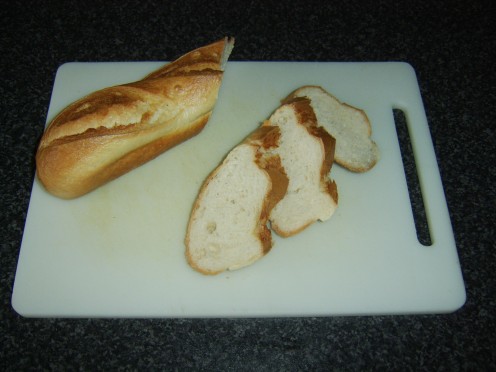 French stick is sliced at an angle to create bread slices for bruschetta