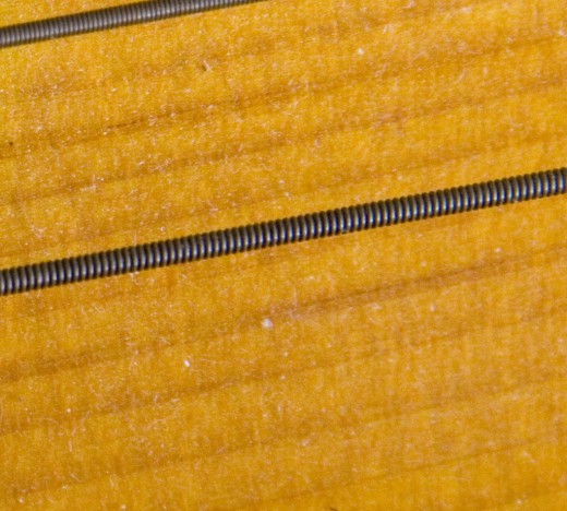 The grain in the wood (or other material) can be hidden by black paint.  Don't assume it's solid wood if your guitar is painted black.