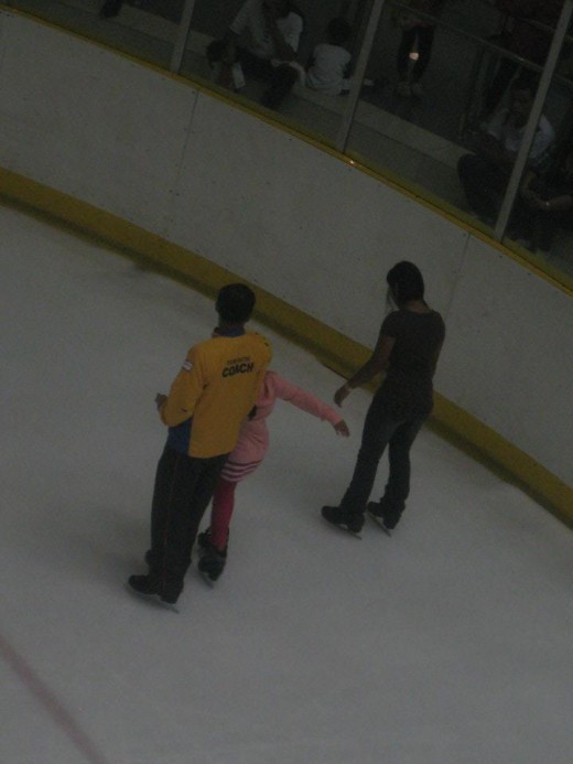 Ice skating coach teaching his student