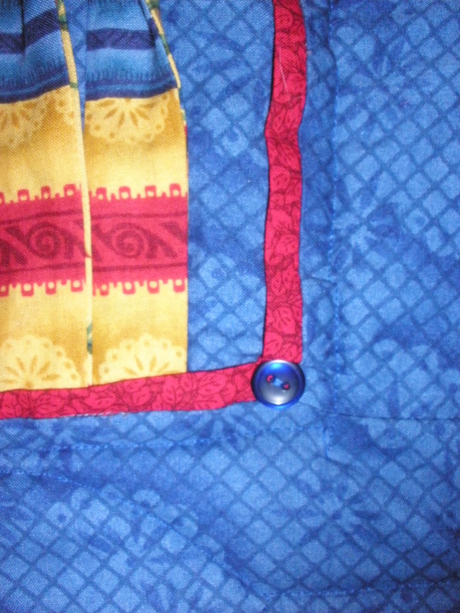 A button adds extra embellishment to the flange. Note that in addition to the red flange, the body of the quilt is made up of a series of flanges.