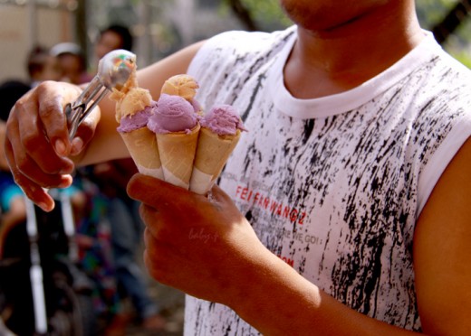 ice cream vendor filling up several cones at a time while children wait behind him