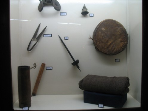 THERE IS A LONG TUBE,A DIVIDER,A EAR PROTECTOR,A BELL,A SWORD,A ROUND PILLOW AND A SUIT CASE KEPT IN CLOCK WISE DIRECTION.NO INFO IN MUSEUM.NO GUIDE.