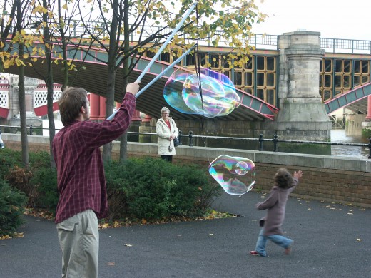 man making huge bubbles and kids loving it.