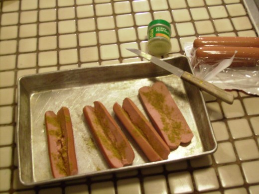 Hot dogs sliced, sprinkled with curry powder and ready for the oven.