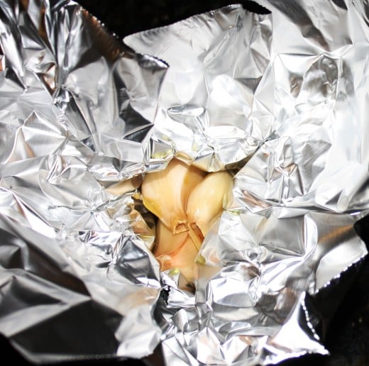 Garlic cloves in foil pocket before being sealed and roasted.
