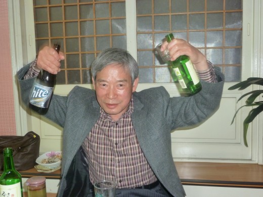 This is my principal holding up a beer bottle and a bottle of soju (rice liquor).