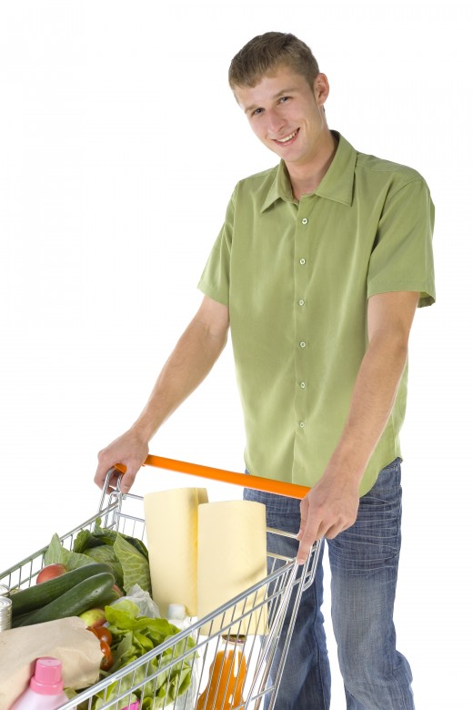 HAPPY SHOPPING MAN by Redbaron Young man standing with full of things trolley. Smiling and looking at camera 