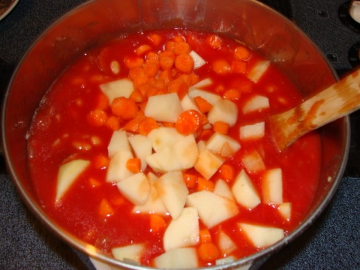 Add the tomato juice, water, and seasonings, followed by the beans, potatoes, and carrots.