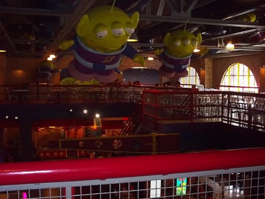 Inside Pizza Planet are giant Little Green Men from Toy Story overlooking the arcade area below