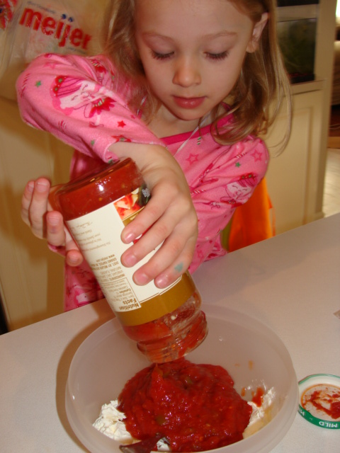 Pouring the salsa into the bowl with the cream cheese.