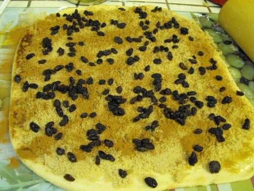 The rolled out dough with butter, brown sugar and raisins